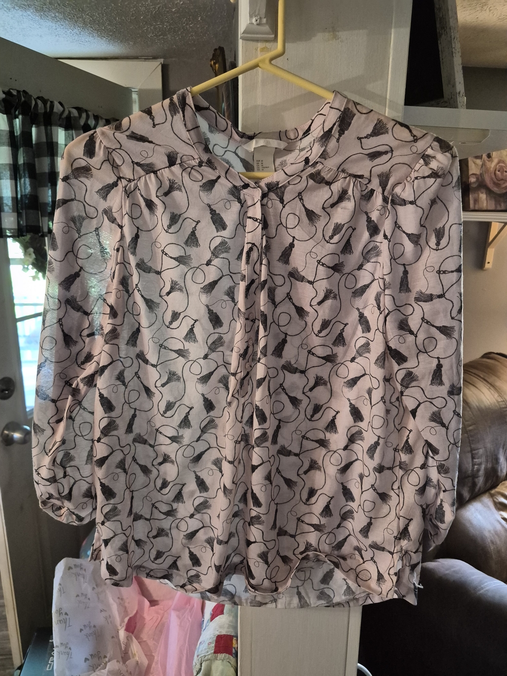 pink H&M blouse features a delicate black tassel and chain graphic print